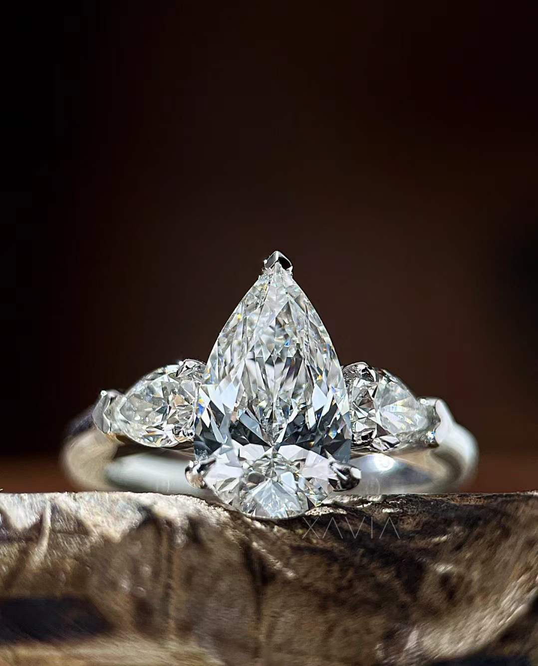 close-up macro view of Novarae pear cut lab grown diamond engagement ring with tapered pear side stones in platinum three-stone setting
